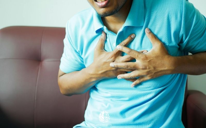 Người đàn ông ôm lấy ngực trái, biểu lộ sự khó thở và đau đớn do cơn hoảng loạn | Tim đập nhanh và hụt hơi là dấu hiệu rối loạn lo âu ở hệ tim mạch | 